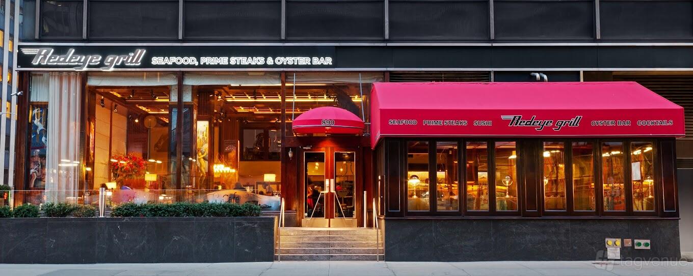 A restaurant with glass windows, a red awning, and illuminated signage at Redeye Grill.