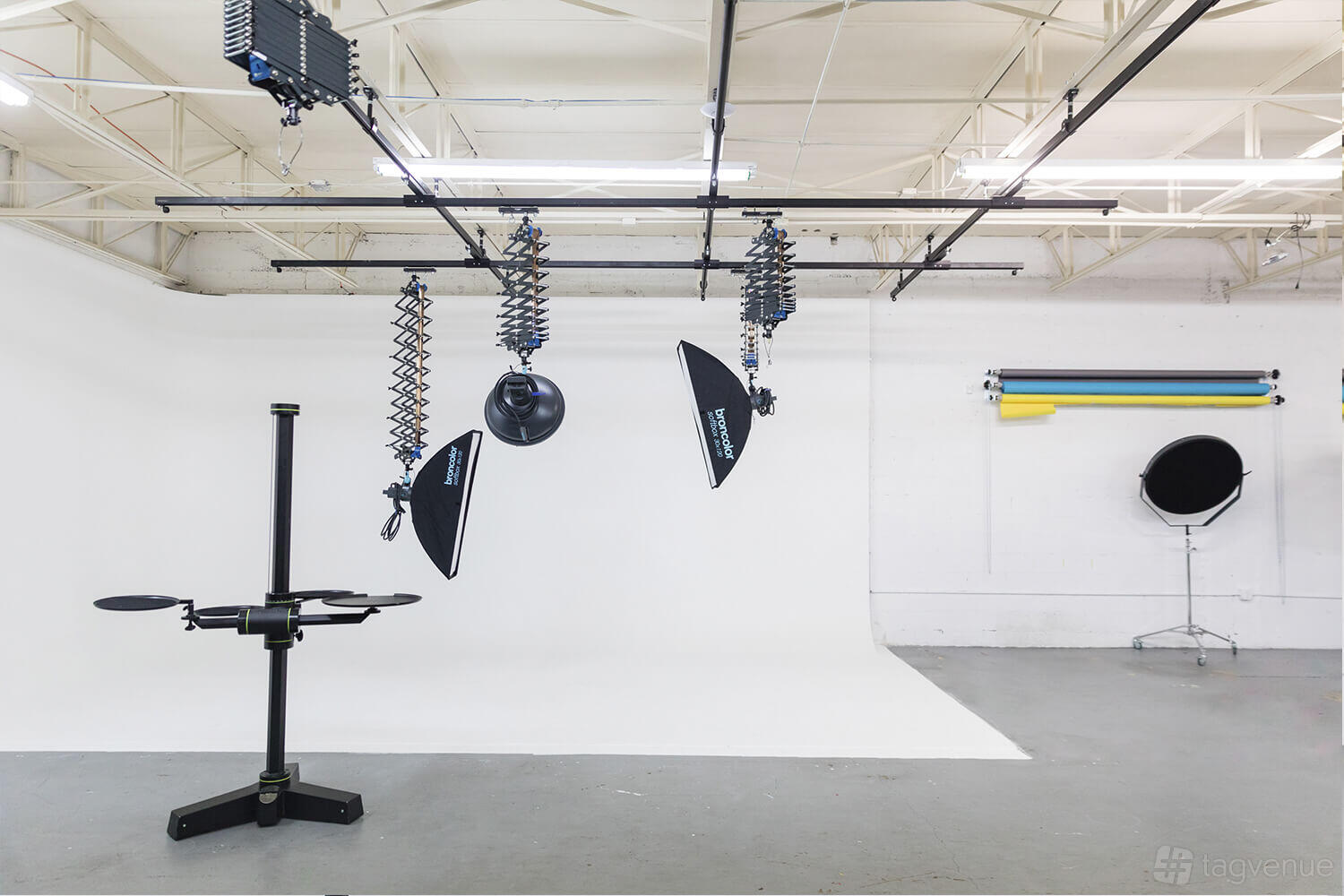 A photo studio with a white cyclorama wall, suspended studio lights, and backdrop rolls at The Fame Studio.