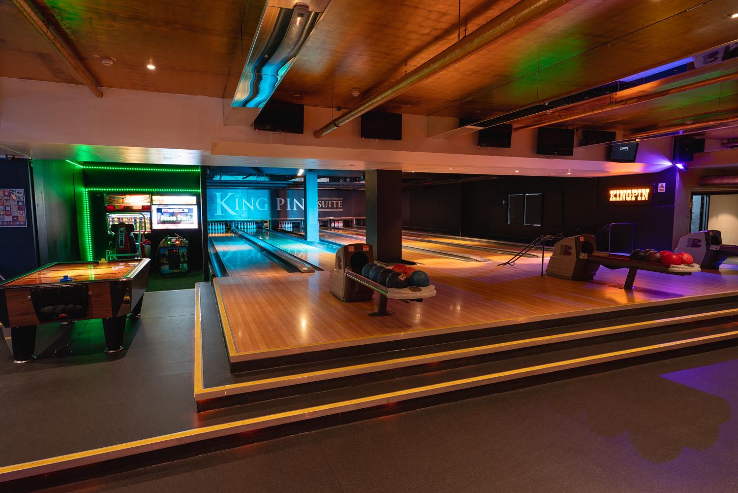 An event space with illuminated bowling lanes, billiard tables, and colorful arcade machines at Bloomsbury Bowling Lanes & The Kingpin Suite.