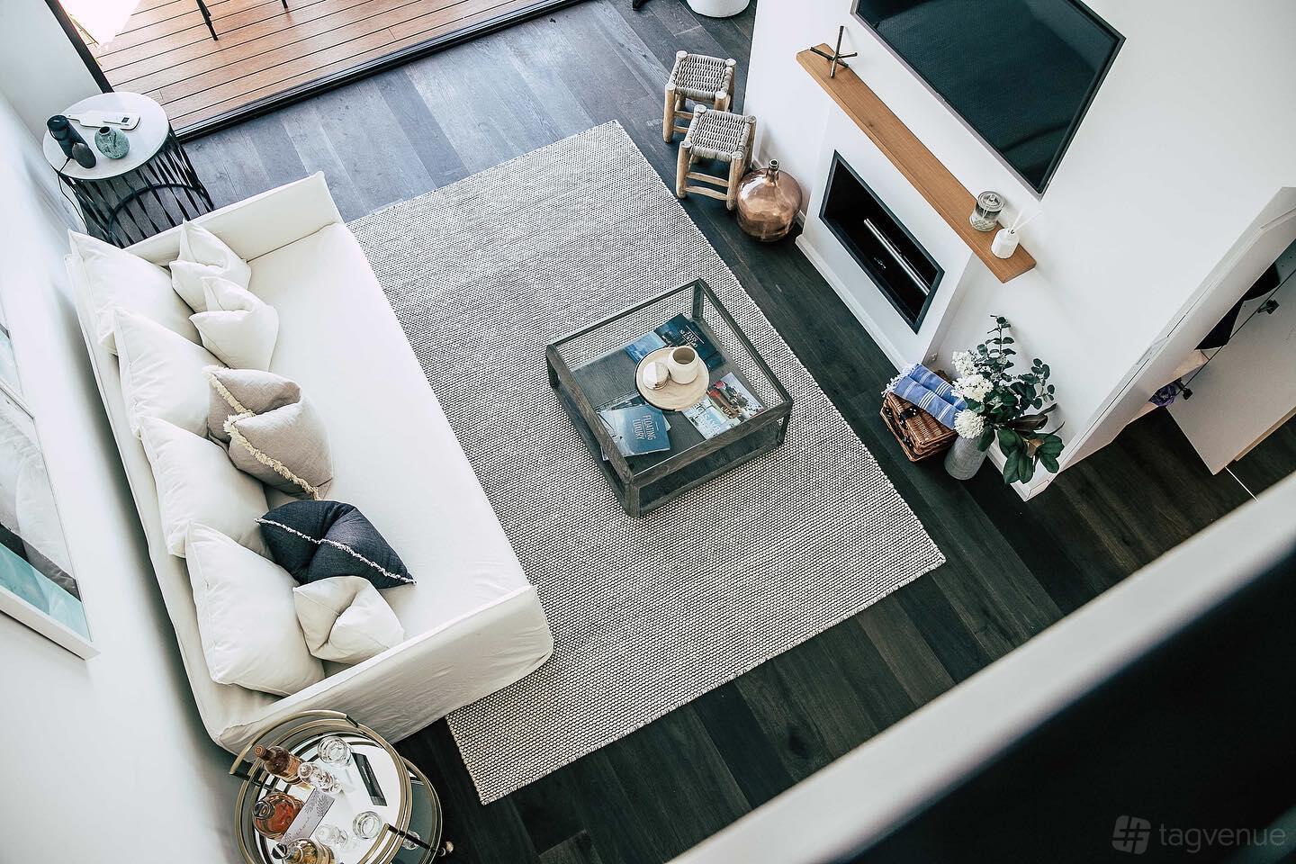 An event space in a hotel with a white sectional sofa, fireplace, wall-mounted TV, and neutral decor at Lilypad Palm Beach.