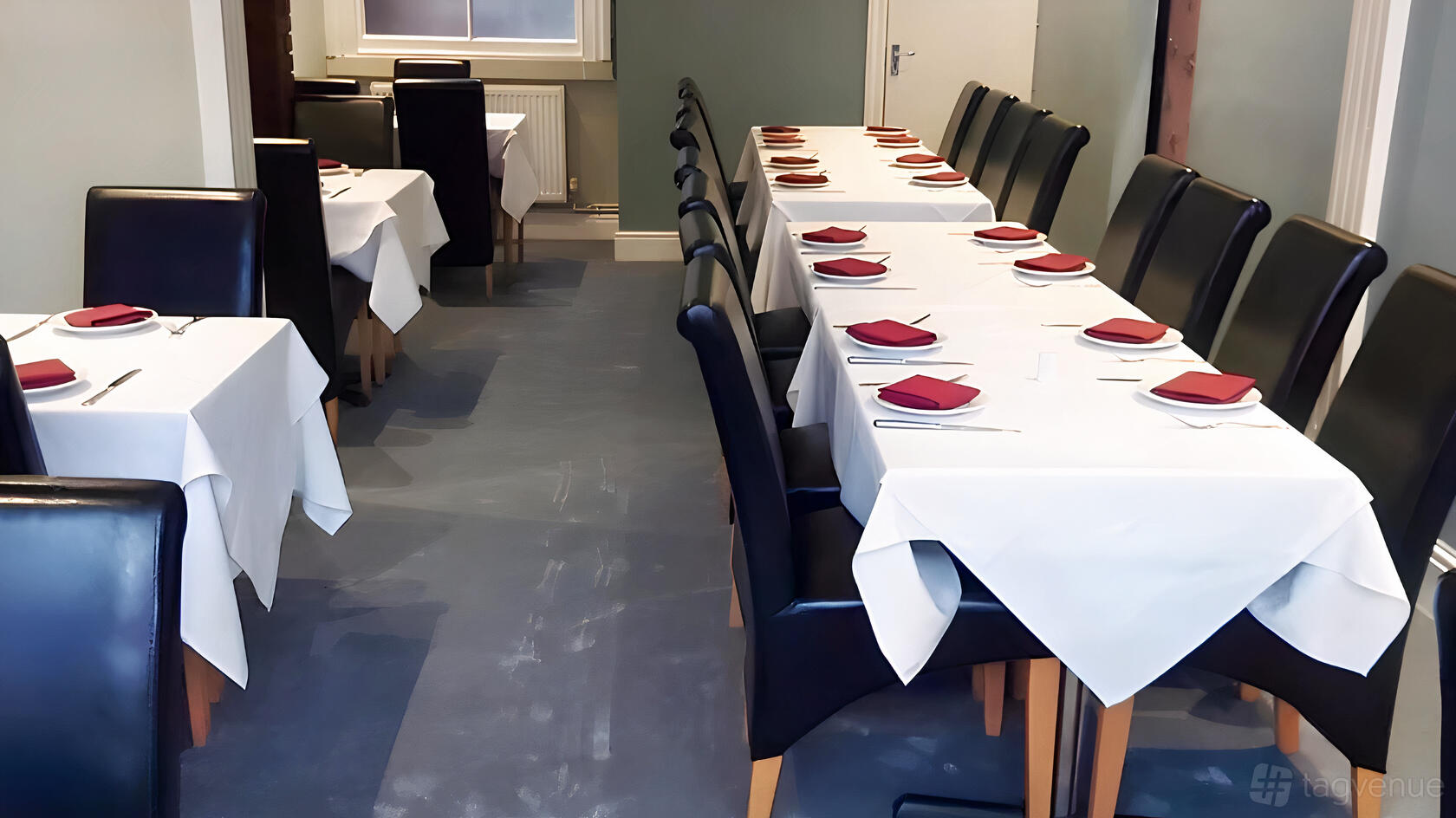 An event space in a restaurant with white tablecloths, dark leather chairs, and red napkins at Dilshad Indian Restaurant.