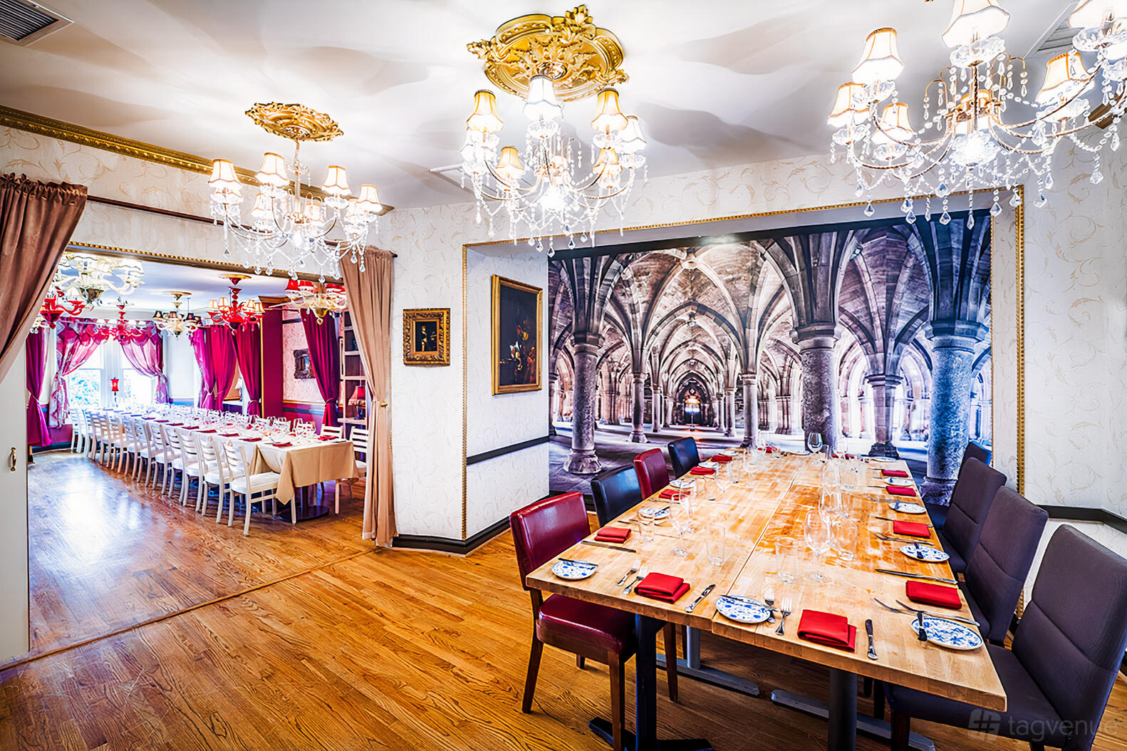 A dining room with long wooden tables, red napkins, crystal chandeliers, and ornamental wallpaper at Bistro Cacao.