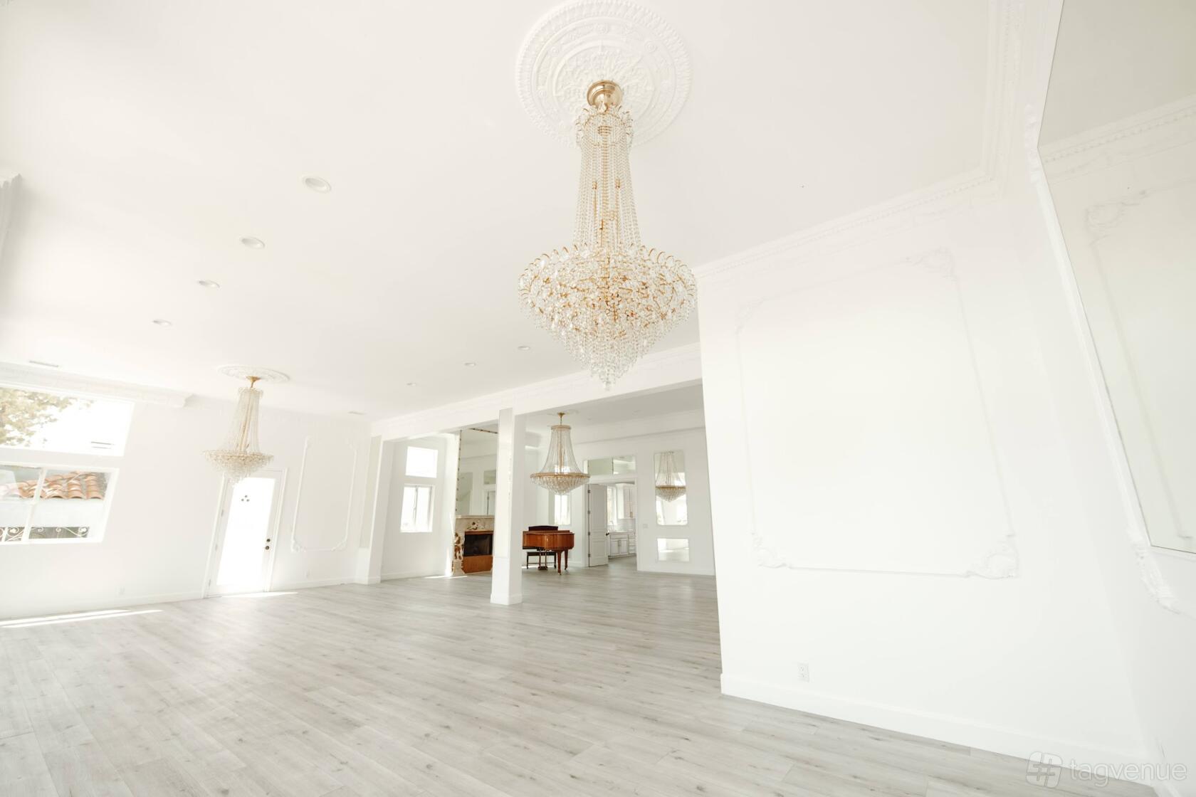 A house with crystal chandeliers, white paneled walls, and light wood floors at Century City Mansion.