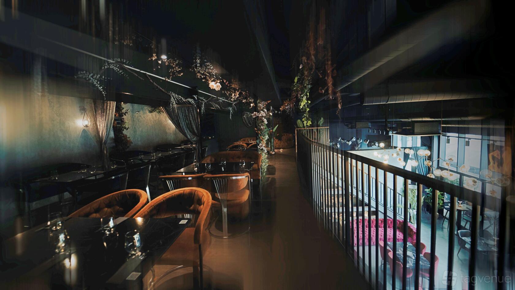 A restaurant with velvet armchairs, dim lighting, and hanging greenery at Kaboom Lounge & Restaurant.