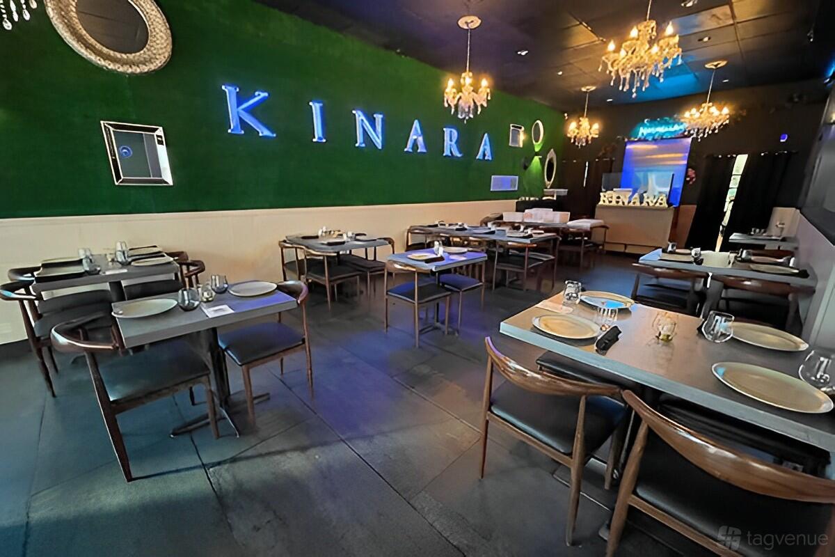 A restaurant with green accent walls, chandeliers, and neatly set tables at Kinara Fusion Kitchen.