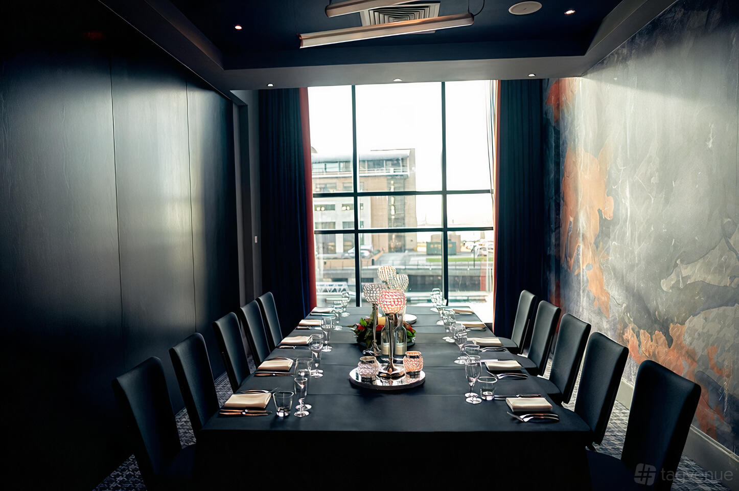A dining room with a long table set for a meeting, black chairs, and floor-to-ceiling windows at Malmaison Liverpool.