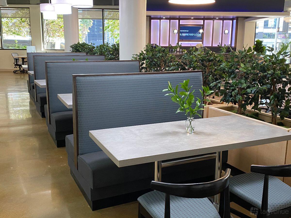 A coworking space with booth seating, potted plants, and large windows at Wilshire1001.