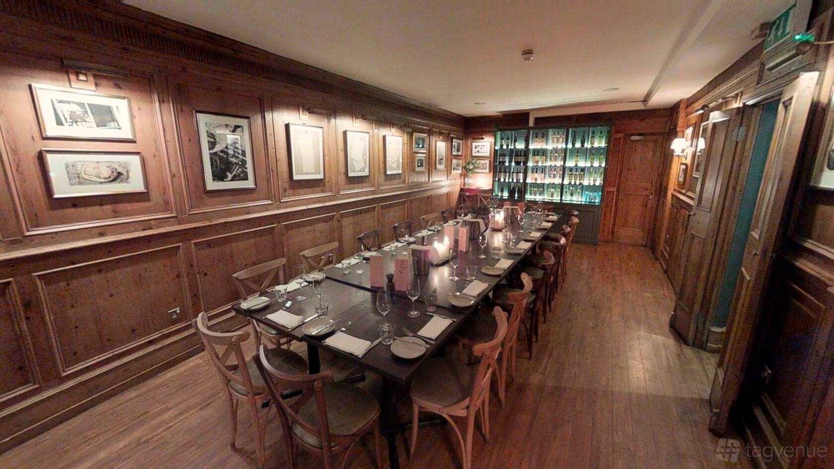 A restaurant dining room with wood-paneled walls, framed artwork, and a long set table at Brasserie Blanc Chancery Lane.