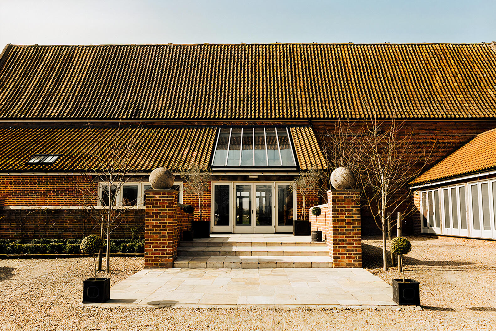 A barn venue with a tiled roof, large central entrance, and brick pillars at Godwick Great Barn.