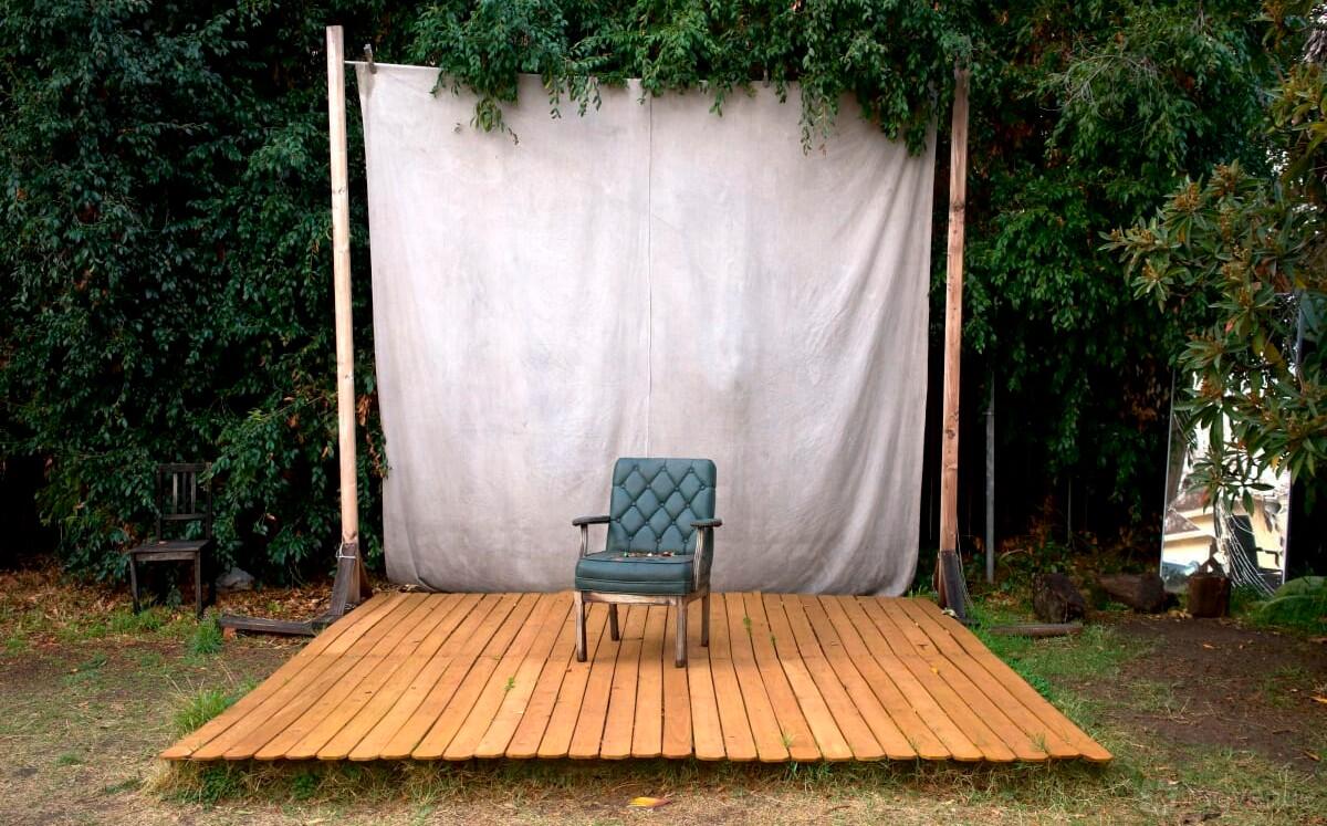 A photo studio with an outdoor wooden platform and a single chair in front of a canvas backdrop at Hammond Space.
