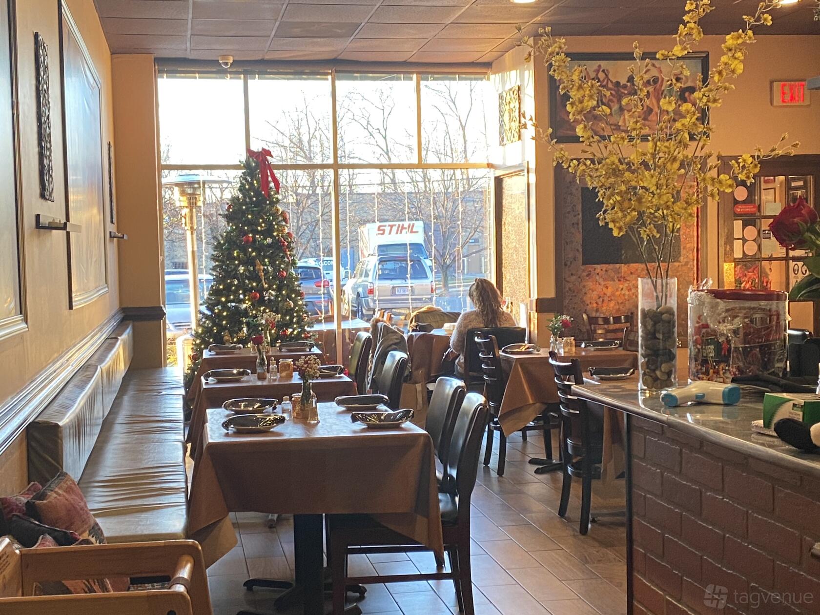 A restaurant with tan tablecloths, a decorated Christmas tree, and floor-to-ceiling windows at Afghan Bistro.