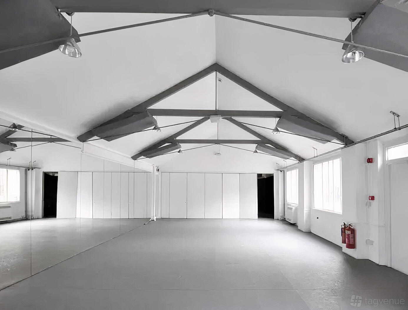 A dance studio with mirrored walls, exposed beams, and large windows at Rhythmic Health and London School of Flamenco.