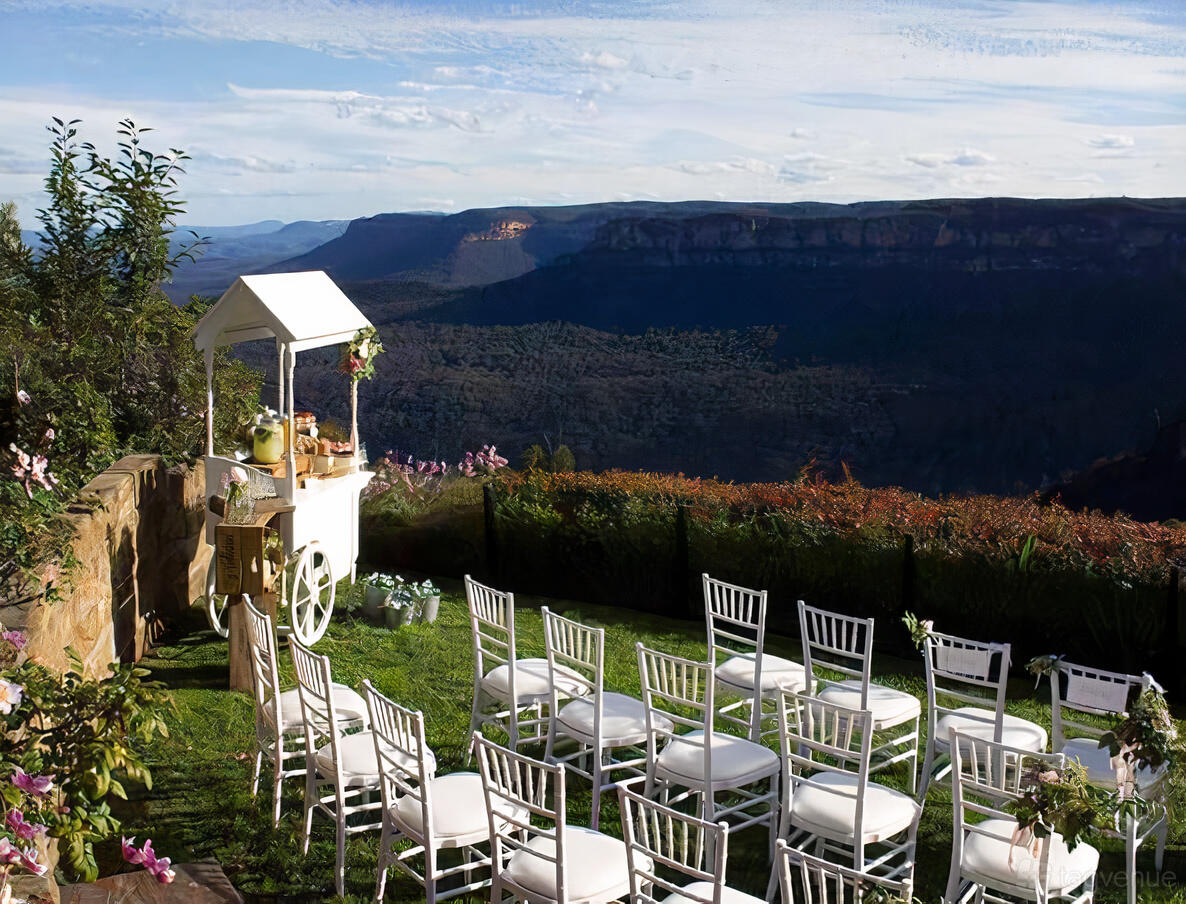 An outdoor hotel space with white chairs on a grassy lawn overlooking mountain views at Echoes Boutique Hotel & Restaurant.