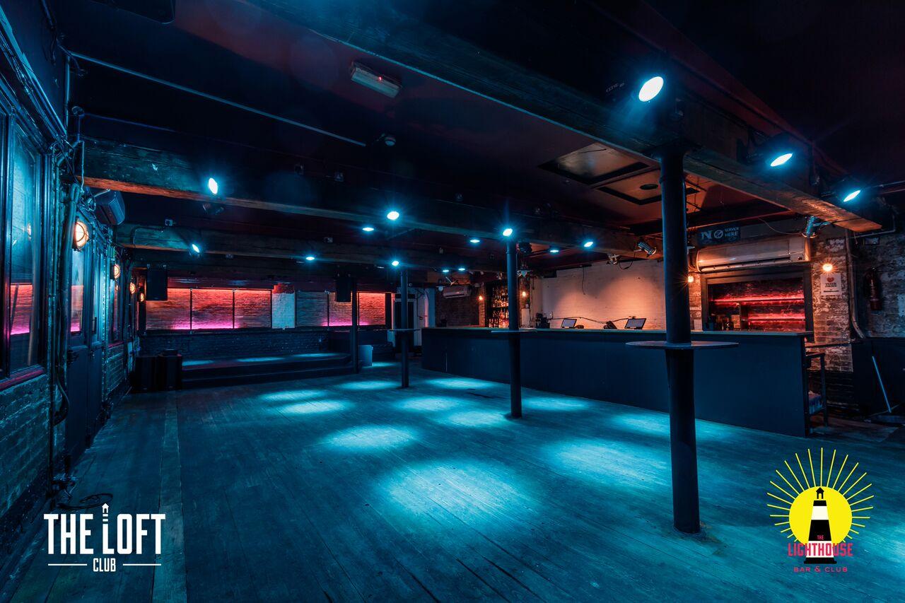 A nightclub lounge with exposed beams, wooden floors, and blue lighting at Lighthouse Bar & Nightclub.