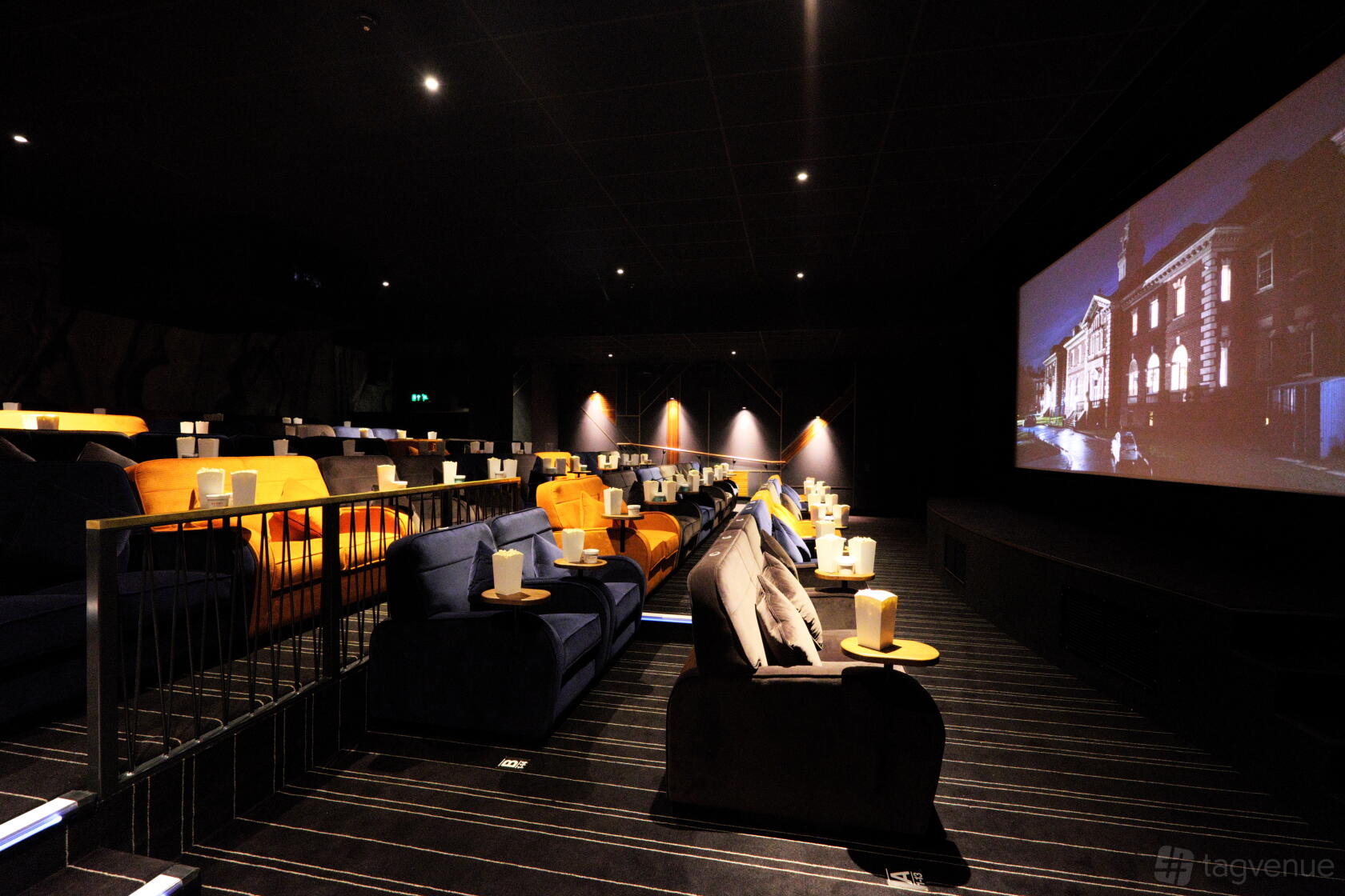 A screening room with plush armchairs, side tables, and a large screen at Everyman Altrincham.