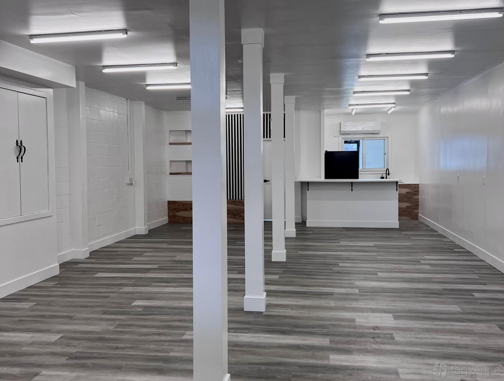 An event venue with wood-look flooring, white columns, and exposed ceiling lights at Contemporary and Modern Studio.
