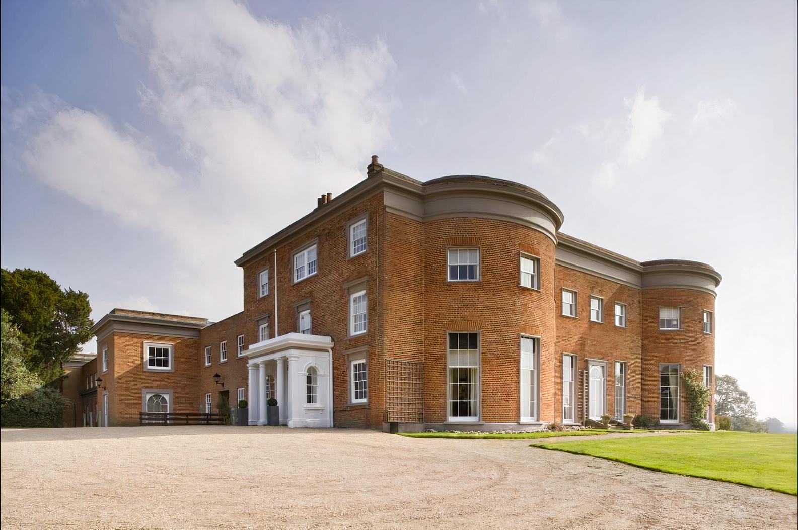 A historic building with curved brick facades, large windows, and a gravel driveway at Highfield Park.
