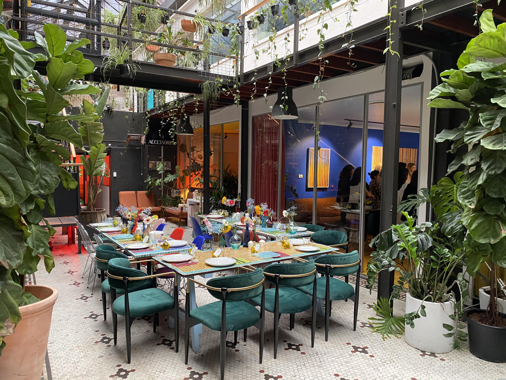 An event space with floor-to-ceiling windows, lush plants, and a long table set with colorful decor at Revolver Lane.