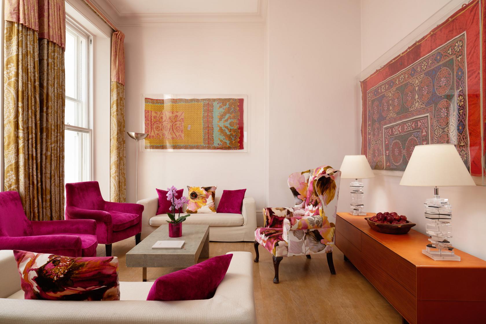 A hotel meeting room with magenta velvet chairs, large windows with curtains, and framed artwork at The Pelham Hotel.