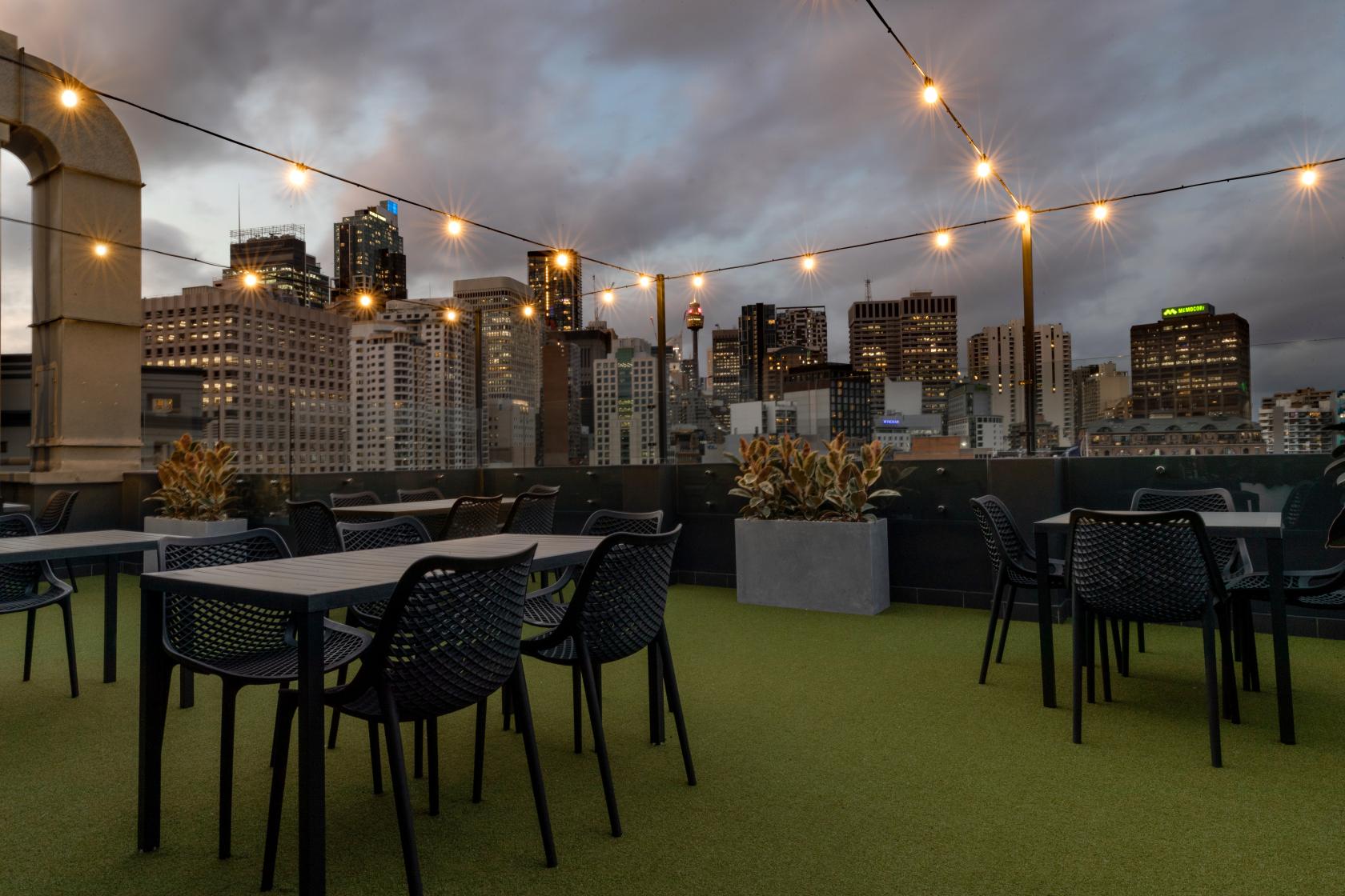 An open air rooftop venue with string lights, city skyline views, and outdoor seating at The Surry Rooftop.