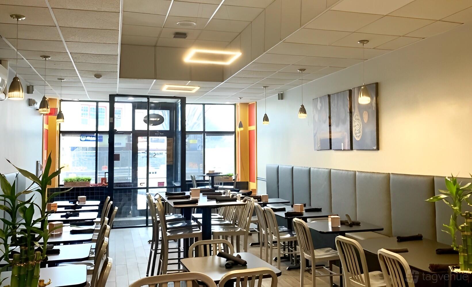 A restaurant with metal chairs, simple square tables, pendant lighting, and framed wall art at Masala Square Indian Kitchen.