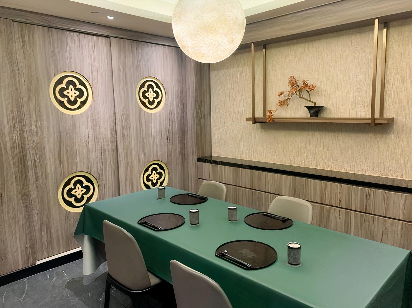 A dining room with a green tablecloth, six chairs, wall decor, and a round pendant light at TAJIMAYA - GREAT WORLD CITY BRANCH.