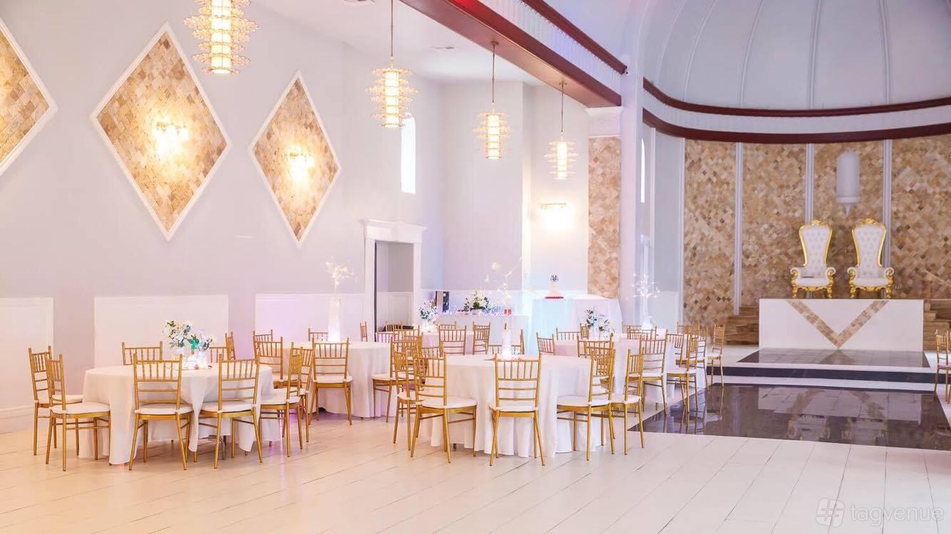 A ballroom with gold chiavari chairs, round tables with white linens, and tall ceilings at The Victorian Banquet Hall.