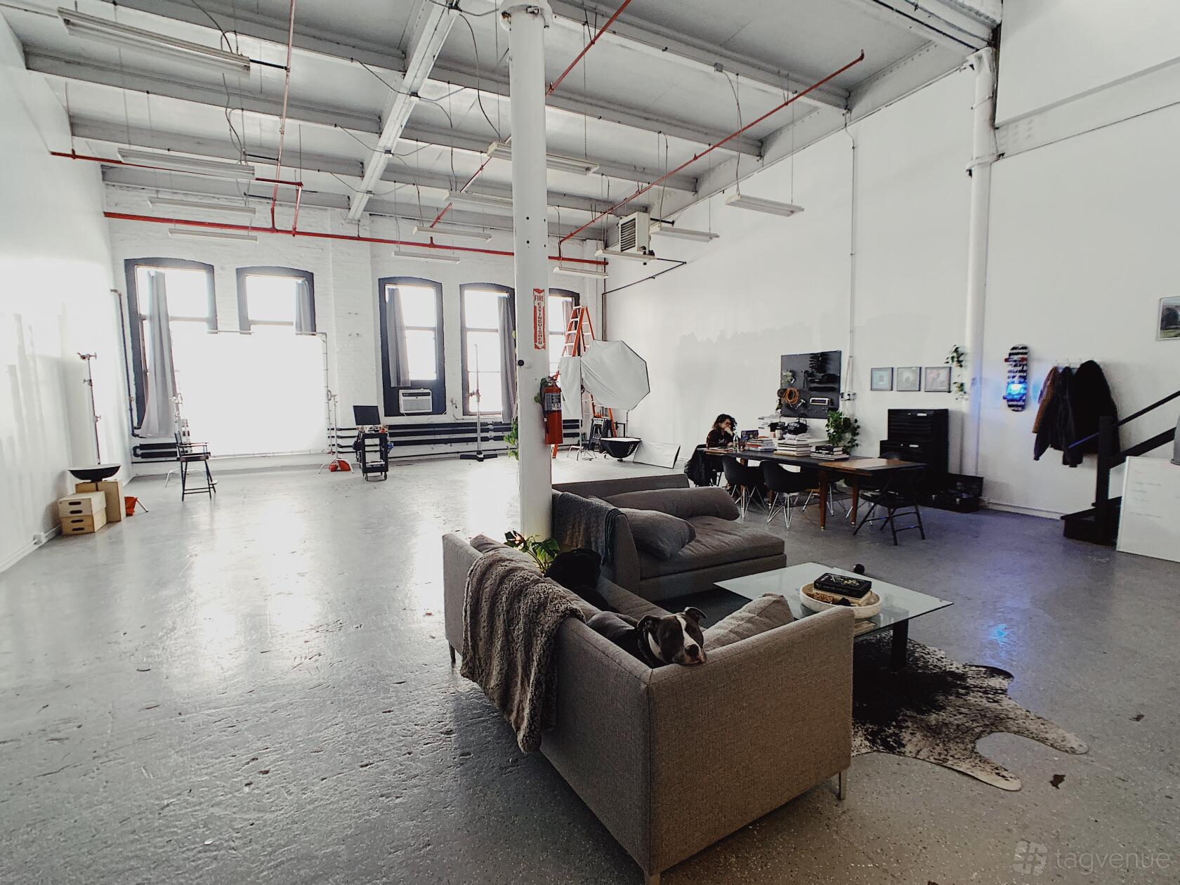A photo studio with high ceilings, white walls, natural light from tall windows, and lounge seating at Rain Studio.