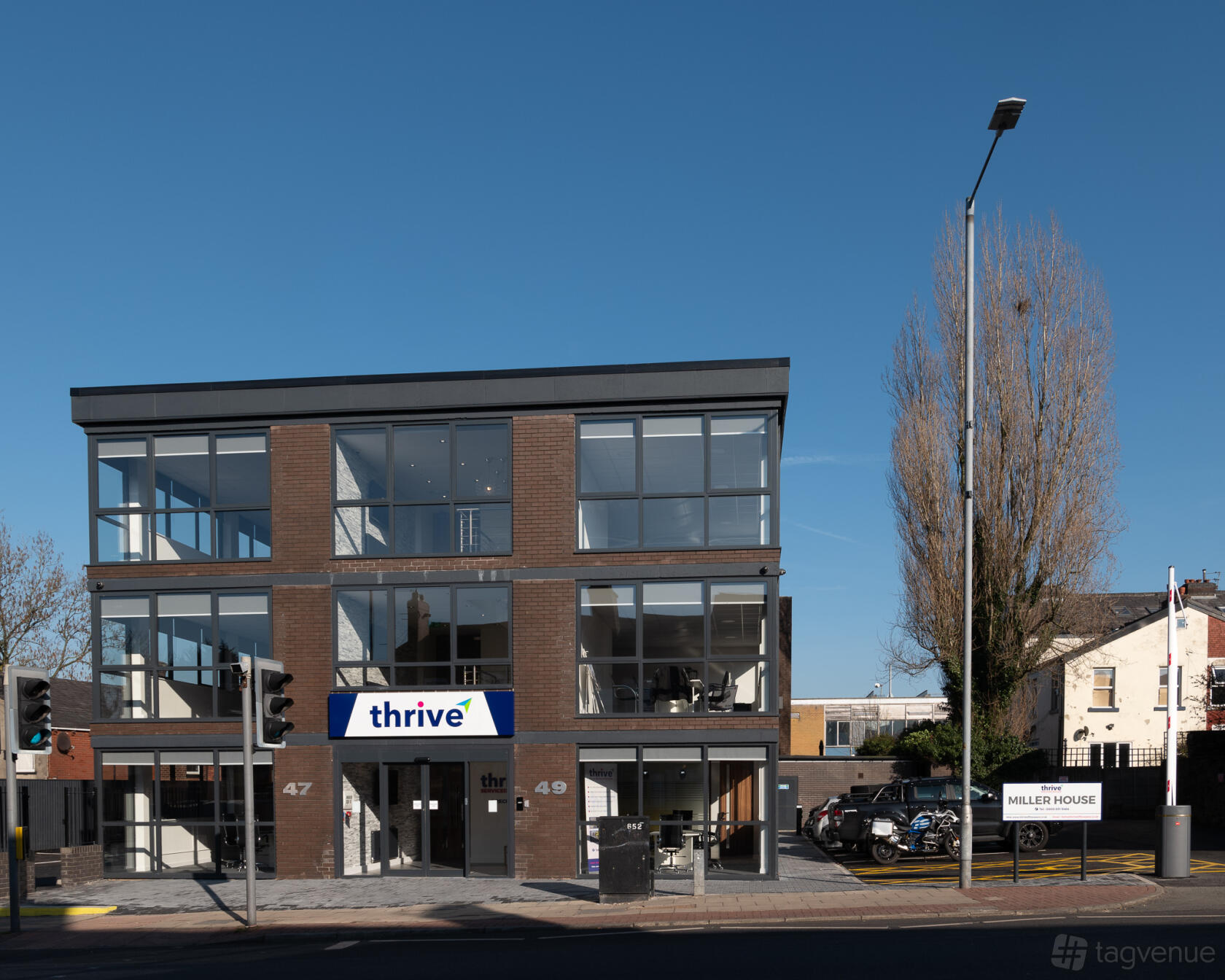 A conference centre with large glass windows, modern brick facade, and street-facing signage at Miller House.