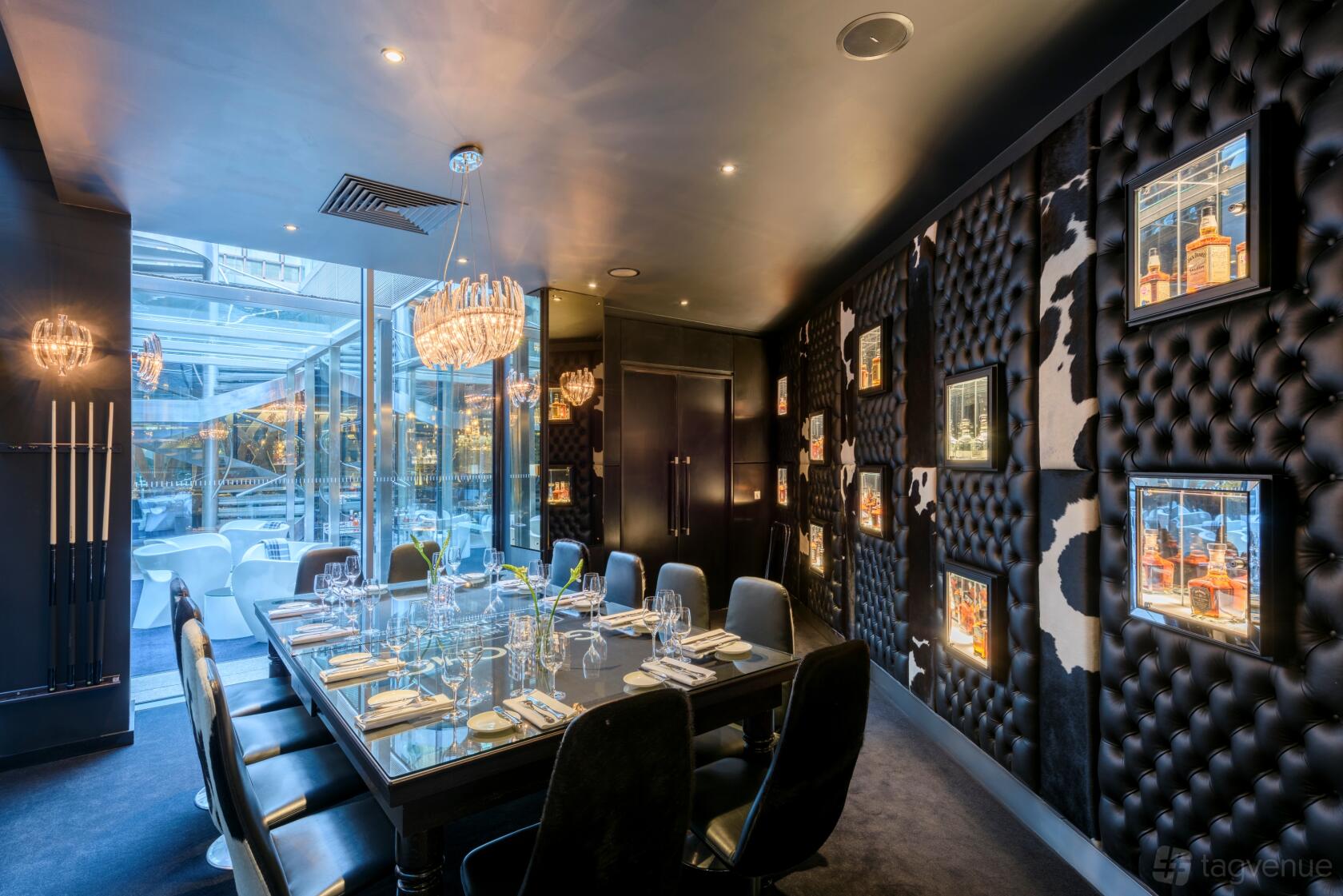 A private dining room with tufted black leather walls, framed whisky displays, and a glass chandelier at Gaucho Broadgate.