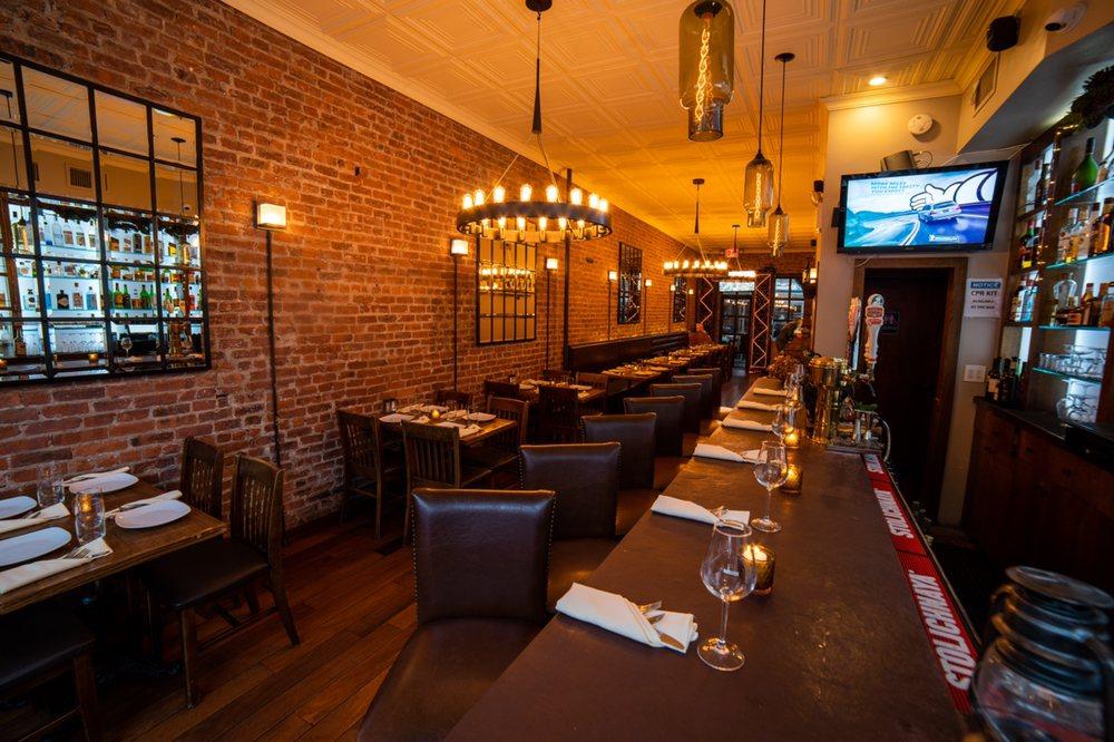 A restaurant with exposed brick walls, pendant lighting, and set tables for dining at Verde on Smith.