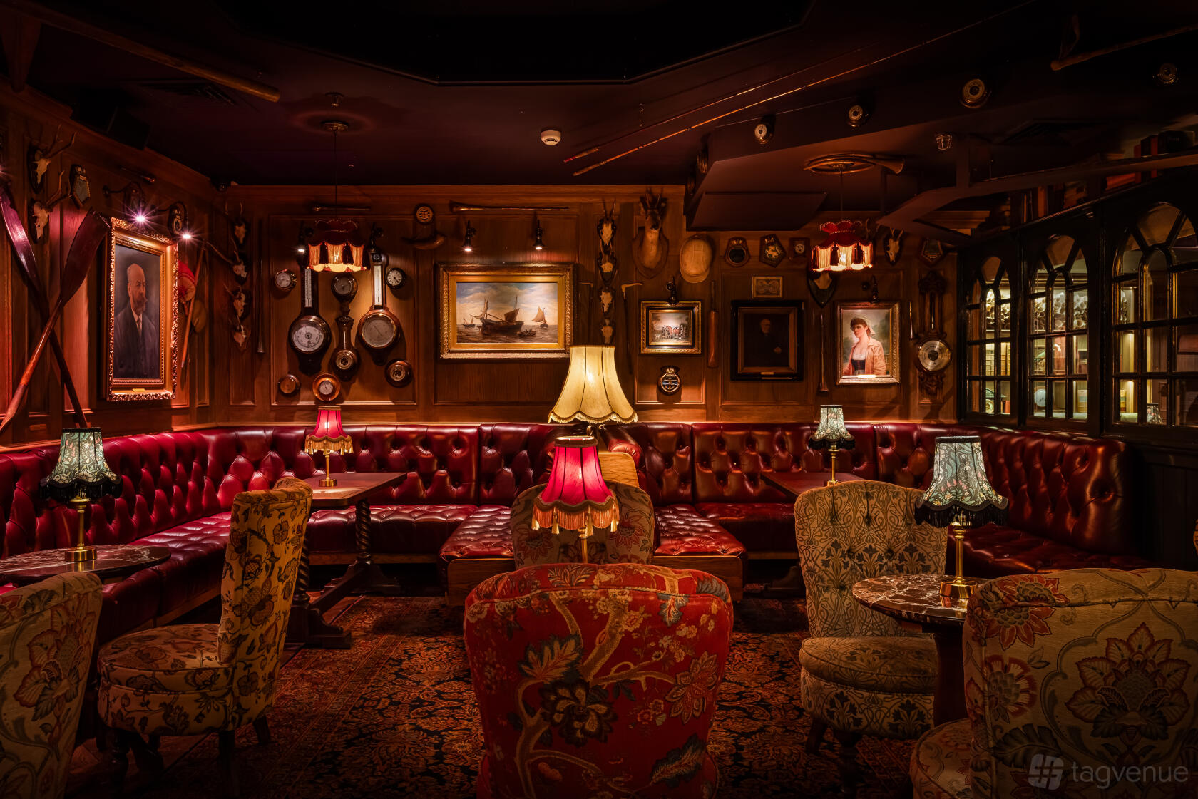 An event space with vintage armchairs, red leather banquettes, antique lamps, and wall-mounted artifacts at Mr Fogg's Society of Exploration.