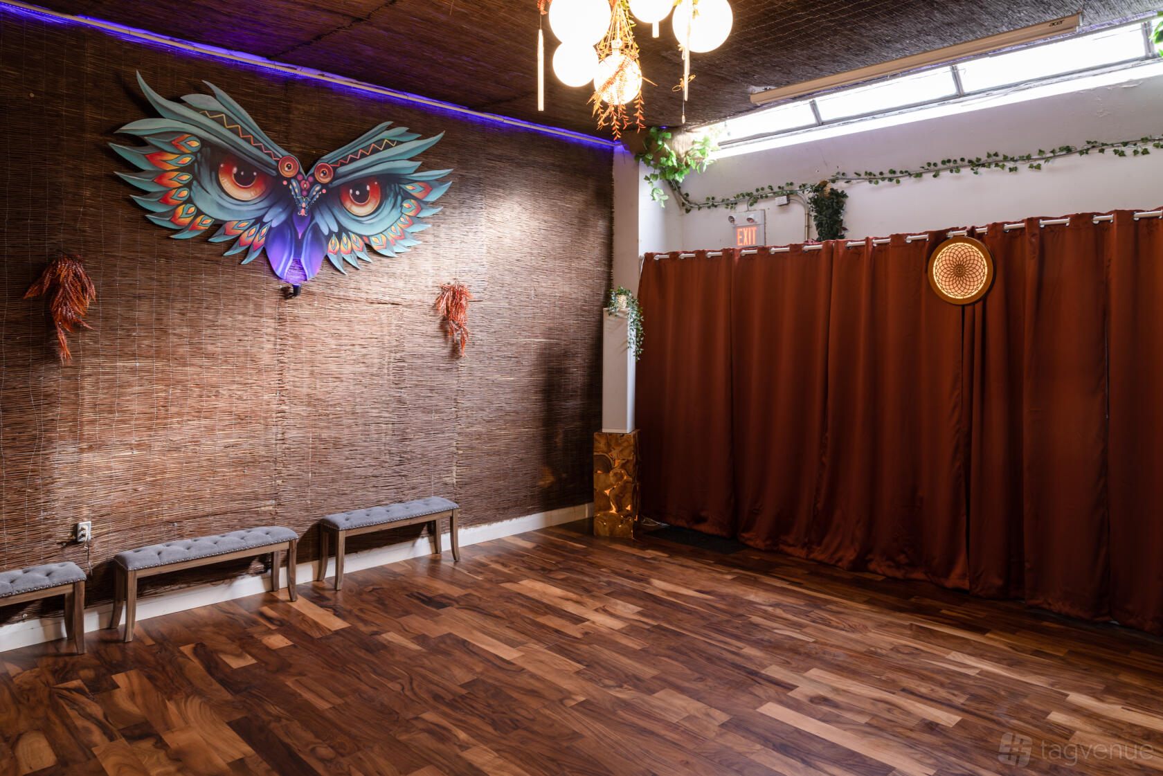 A cafe with wooden floors, rattan walls, an artistic owl wall sculpture, and benches at Alternity.