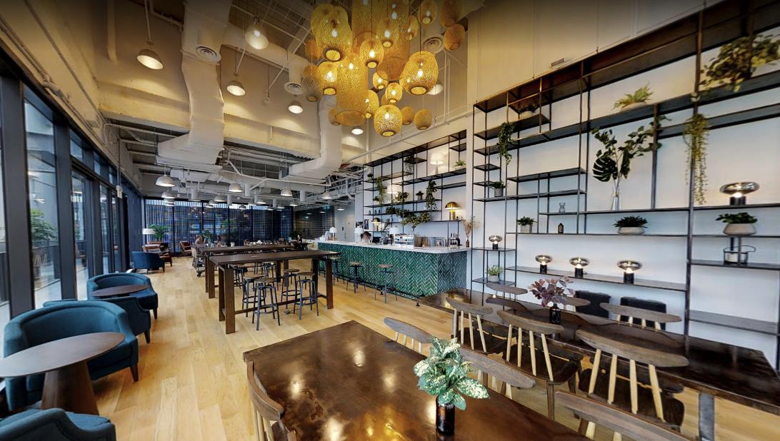 An event space in a coworking venue with hanging wicker lanterns, a tiled bar, and floor-to-ceiling shelves at The Hive Carpenter.