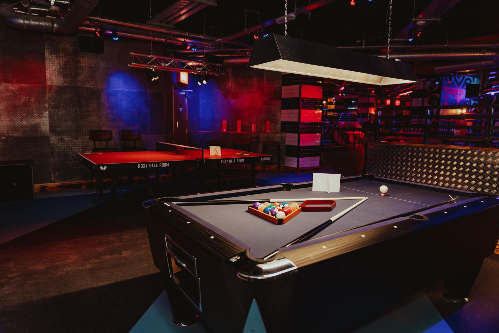 An event space in a bar with a pool table, table tennis, and industrial lighting at Roxy Ball Room Victoria Square.
