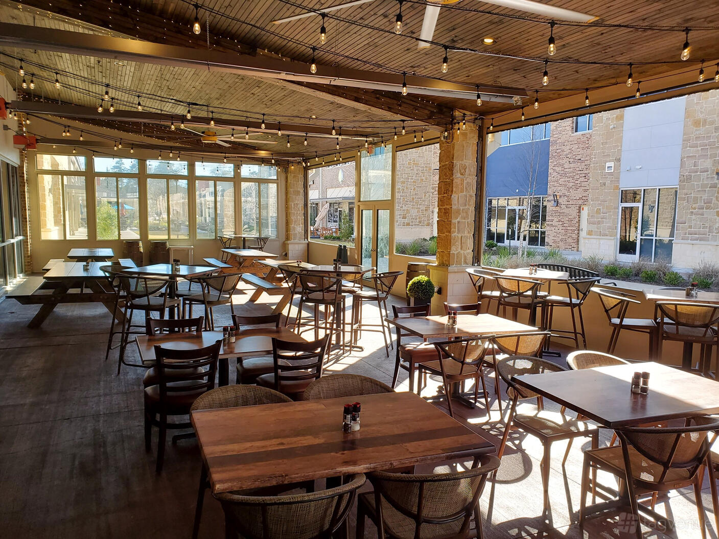 An event space in a restaurant with wooden tables, string lights, and large windows at Citizens Grill.