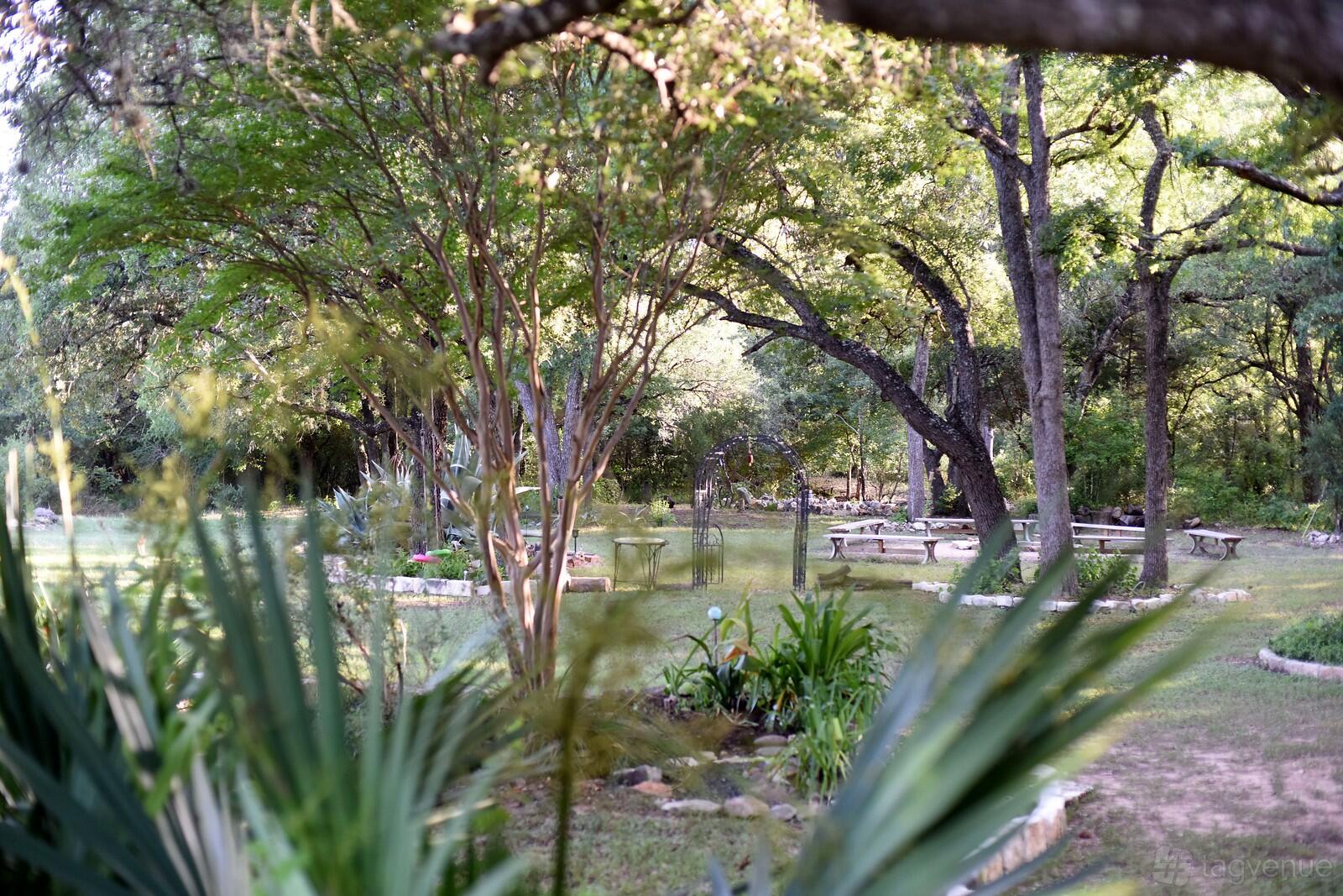 A house surrounded by mature trees, picnic tables, and landscaped gardens at Lotus Bend Sanctuary.