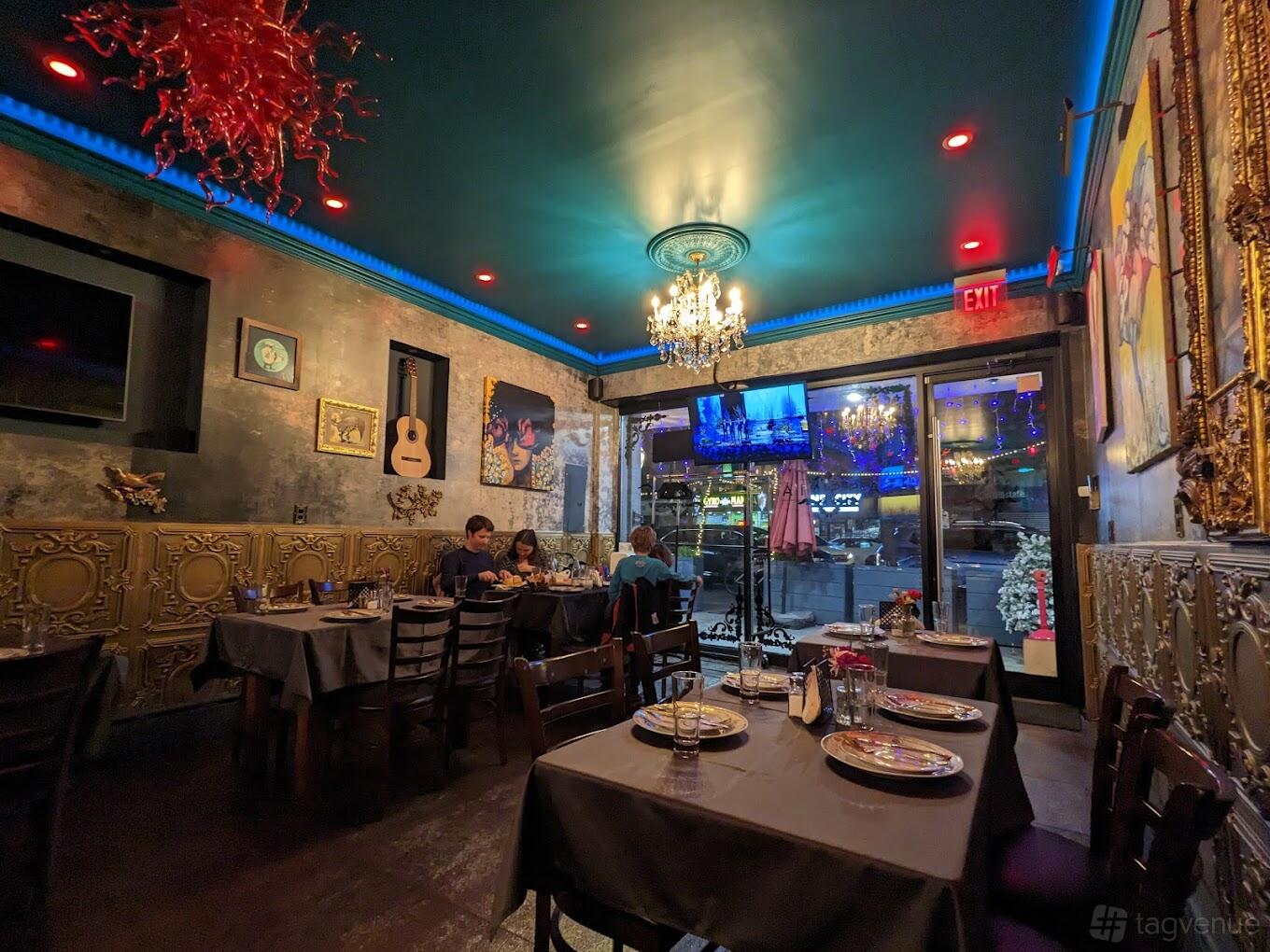 A restaurant with ornate gold wall panels, chandelier lighting, and dark wood tables at ASSAIA.
