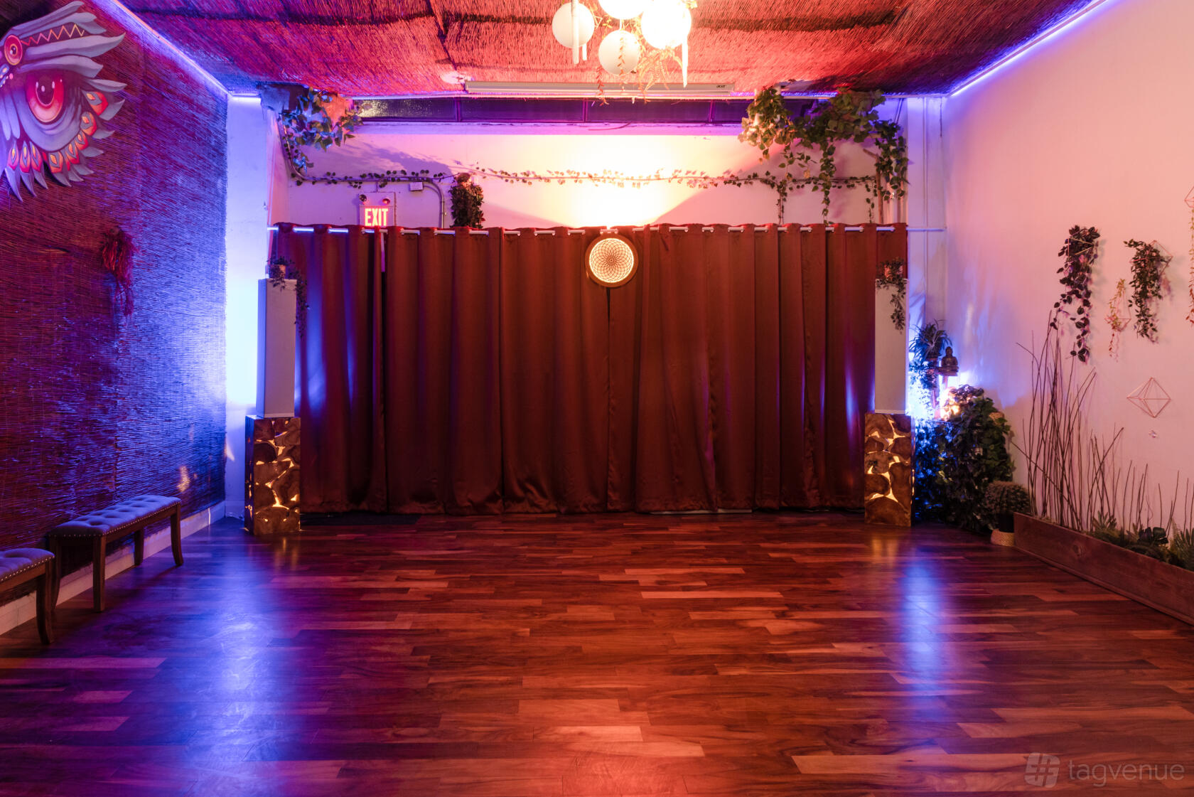 A function room with wood floors, brown drapes, and purple accent lighting at Alternity.
