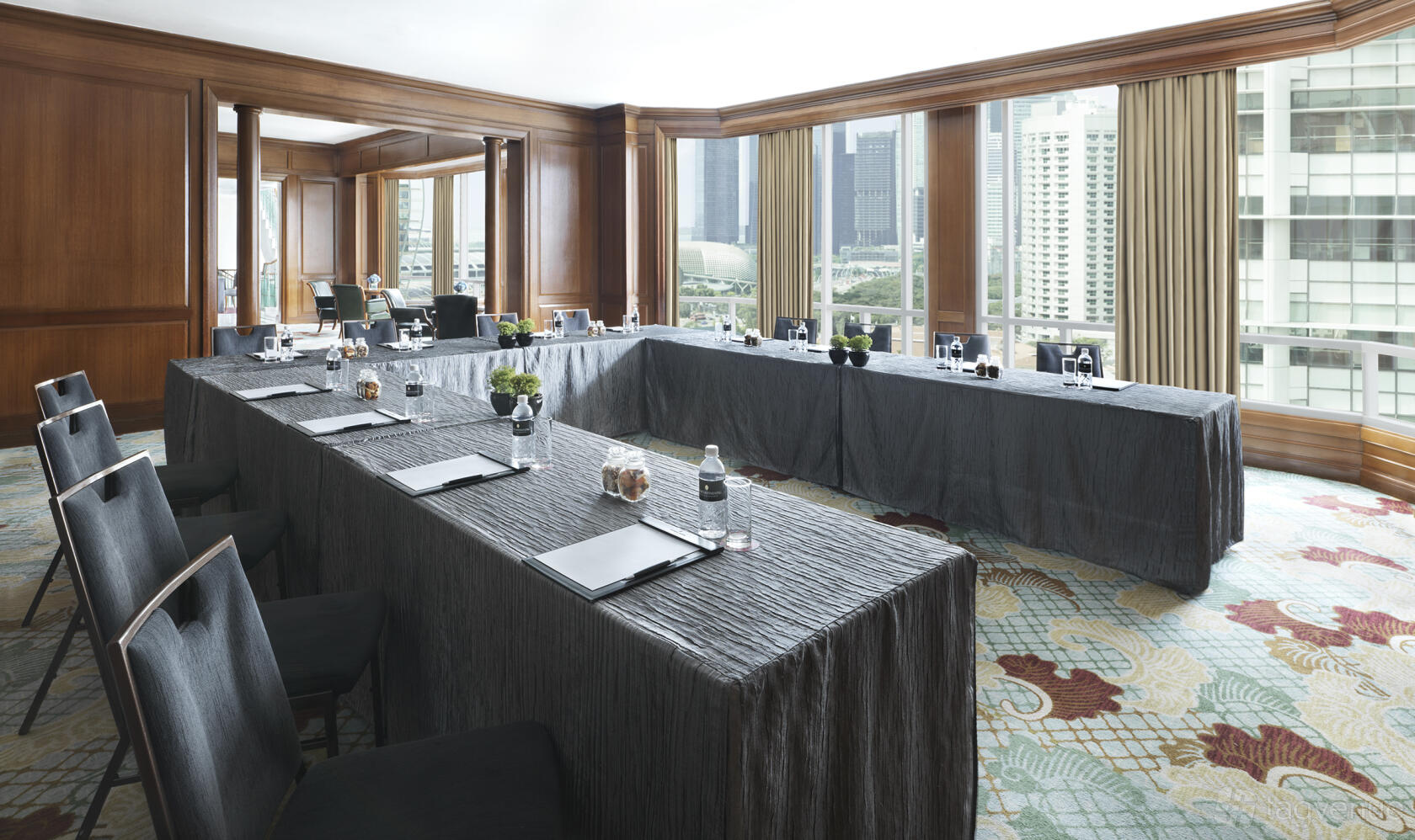 A hotel meeting room with U-shaped tables, large windows offering city views, and wood paneling at InterContinental Singapore.