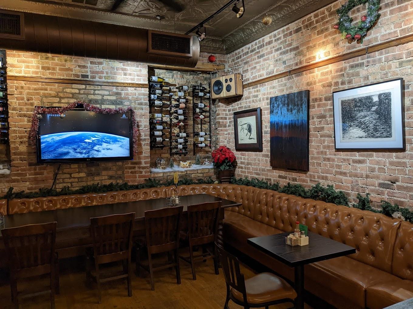 A function room with exposed brick walls, brown leather banquette seating, and wall-mounted wine racks at Port and Park Bistro.