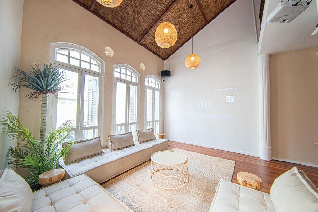 An apartment event room with arched windows, rattan pendant lights, built-in seating, and light wood floors at NORRIS House.