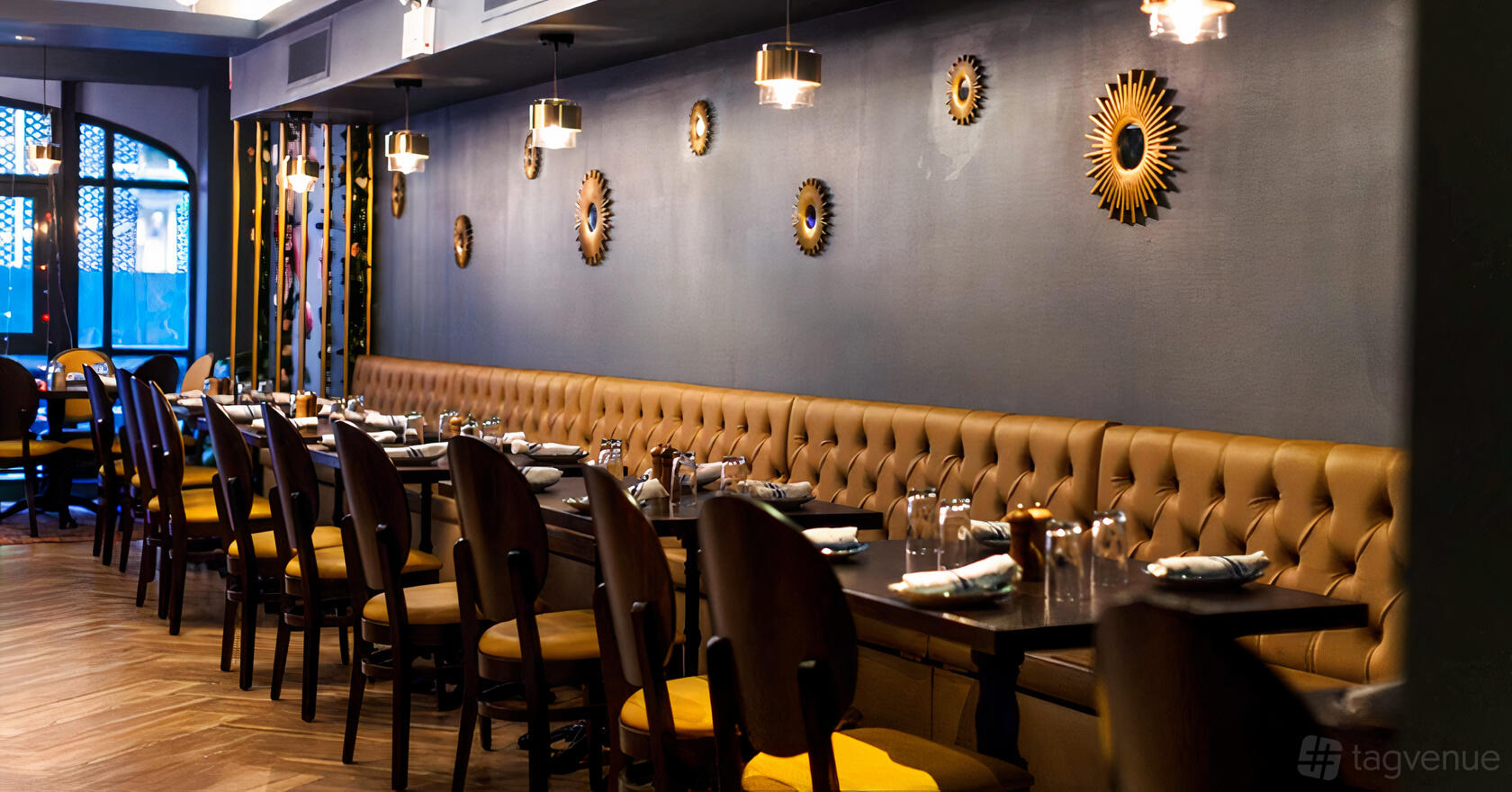 A restaurant with tufted leather banquette seating, wooden tables, and sunburst wall decor at Akdeniz Mediterranean Cuisine.