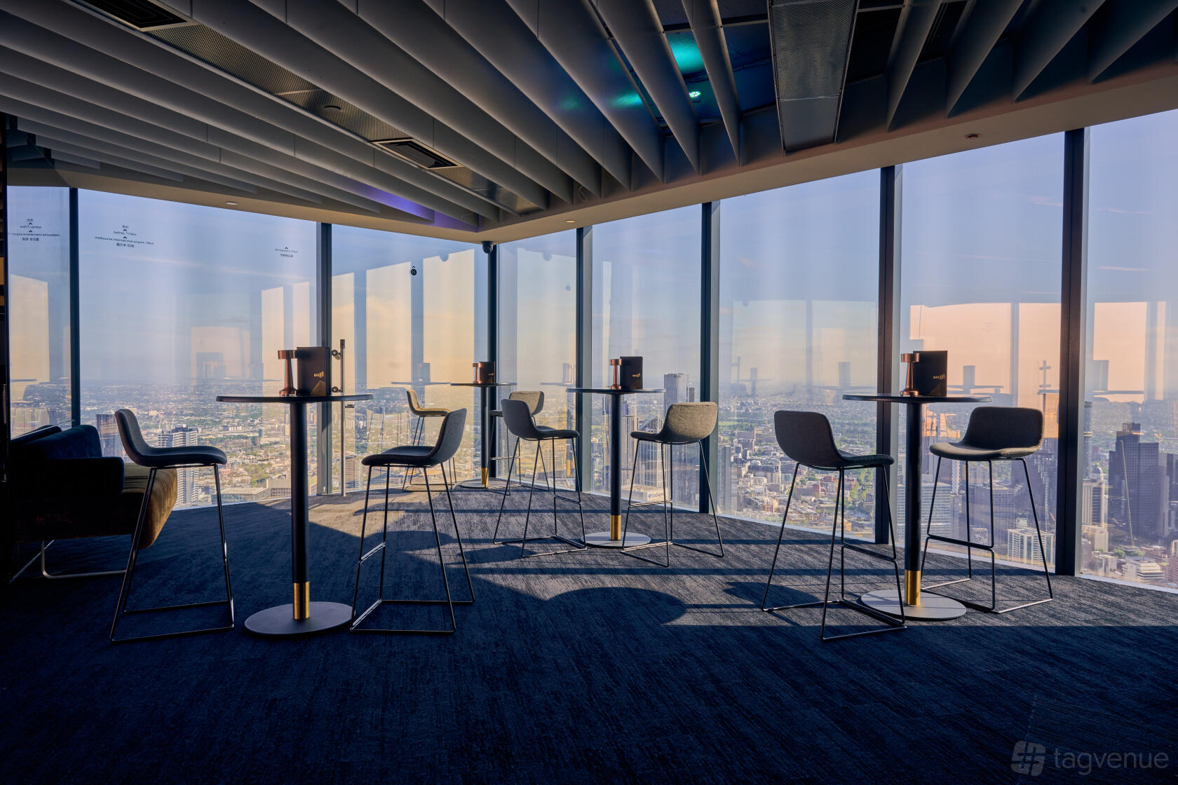 An event venue with floor-to-ceiling windows, high-top tables, and skyline views at Melbourne Skydeck.
