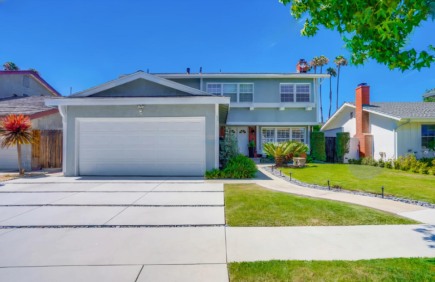 A two-story film and photo studio with a white garage and manicured lawn at Traditional Modernized Home