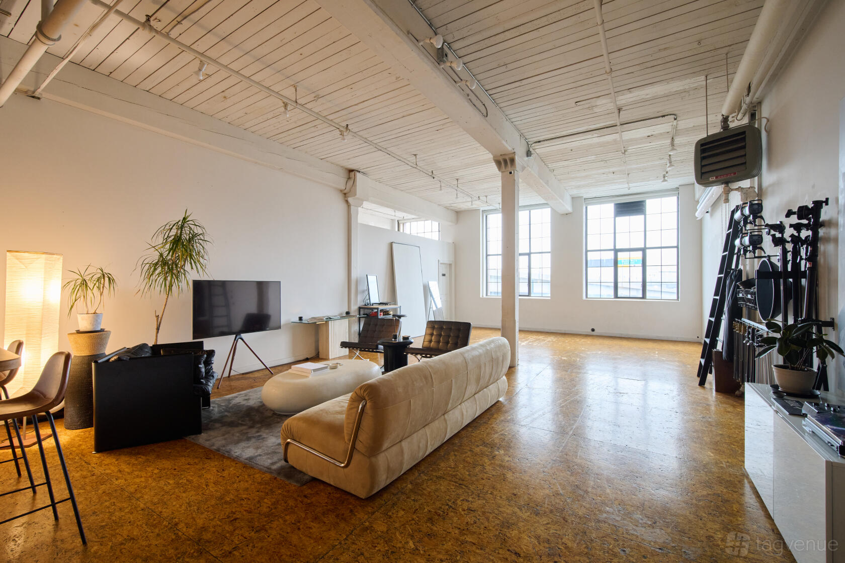 A photo studio in a loft with high ceilings, large industrial windows, and a seating area at Studio 305.