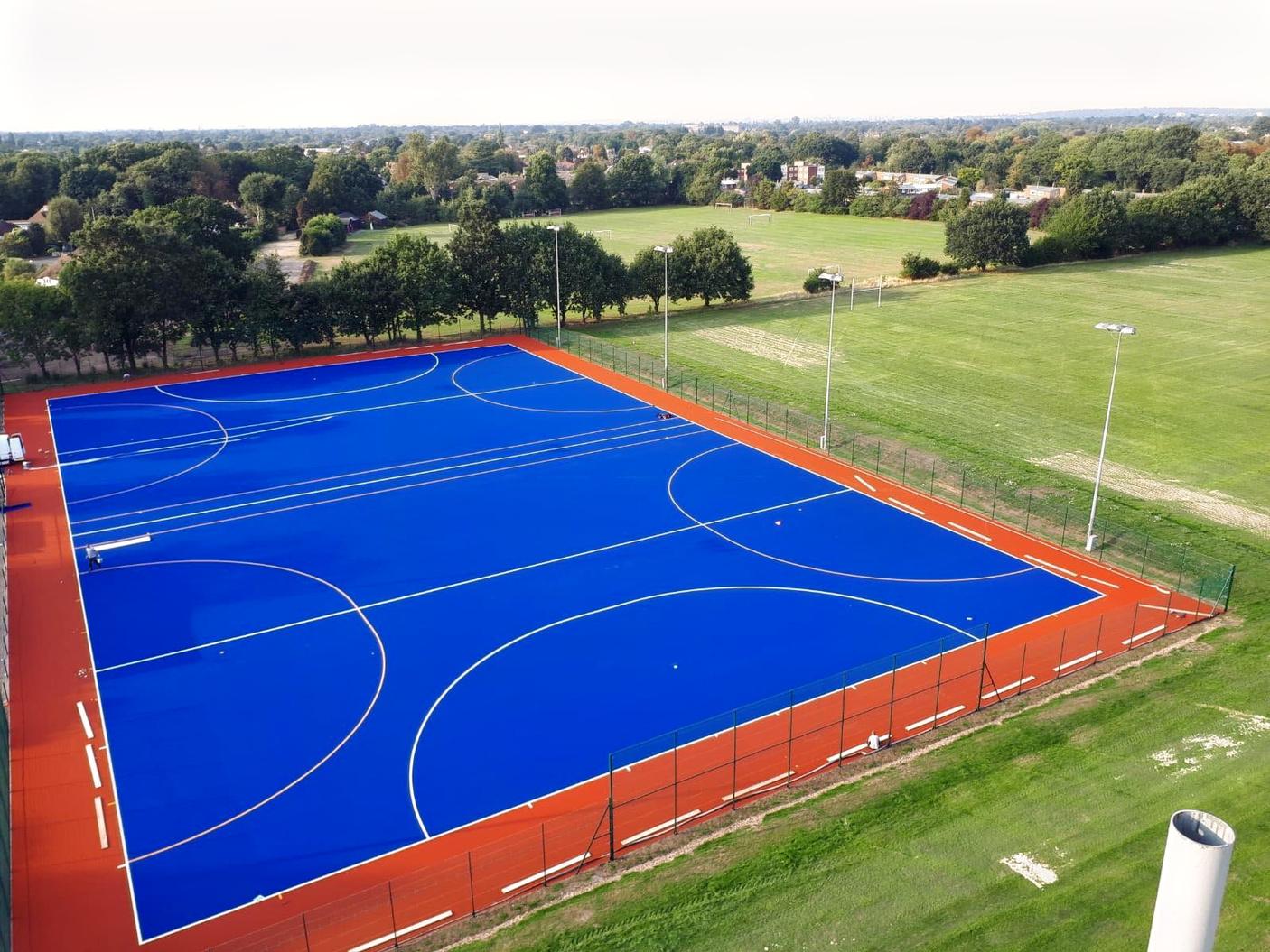 An outdoor sports field with blue artificial turf and white markings at Old Cranleighan Sports Club.