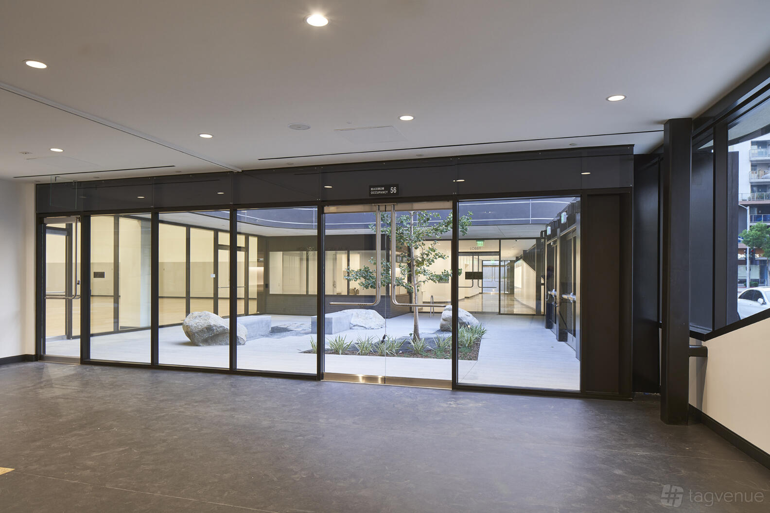 An event venue with floor-to-ceiling windows and a courtyard featuring landscaping and large stones at Terasaki Budokan.