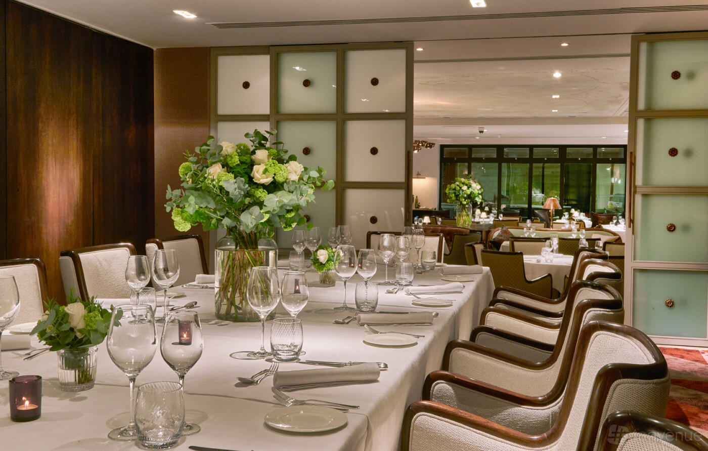 A private dining room with a long table, white linens, floral centerpieces, and glassware at Sartoria.