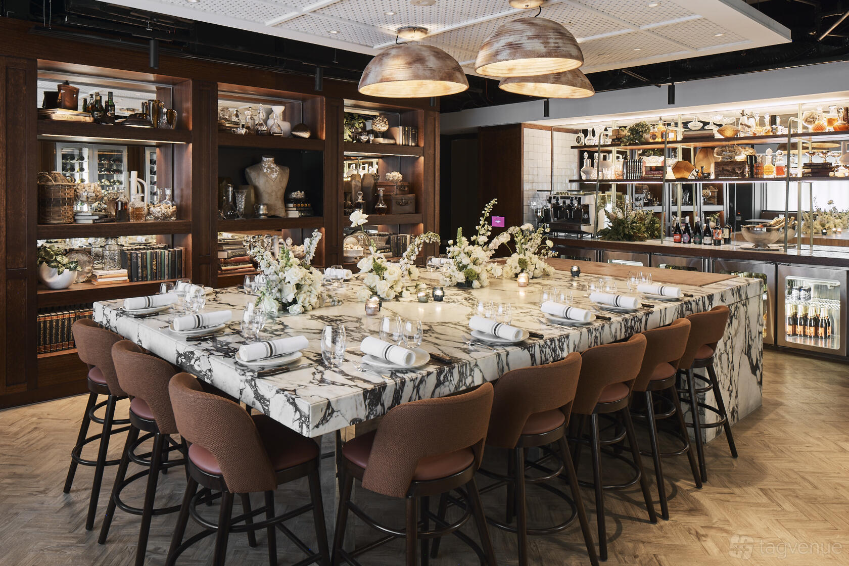 A private dining room with a large marble table, pink upholstered chairs, and floral centerpieces at Bossley Bar & Restaurant.